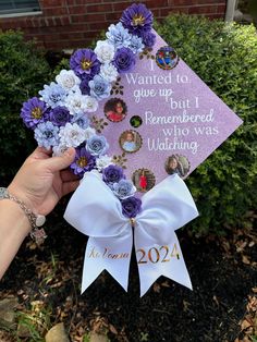 a hand holding a purple and white graduation cap with flowers attached to it that says, wanted to give up but i remembers who was wedding