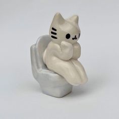 a white cat figurine sitting on top of a rock