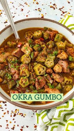 a bowl of okra gumbo is shown on a table with a spoon in it