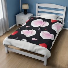 a bed with a black and white bedspread covered in pink hearts on it