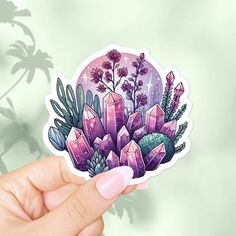 a hand holding up a sticker with crystals and plants