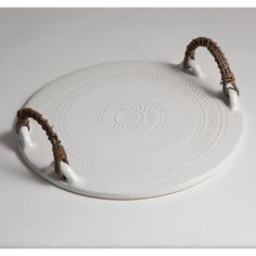 a white platter with two handles and brown rope around the rim, sitting on a table