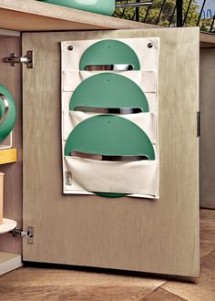 a kitchen cabinet with three green plates hanging from it's side and an oven in the back