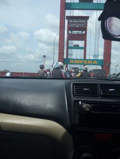 the driver's view from inside a car driving over a bridge with people on it