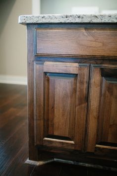 a wooden cabinet with granite top on hard wood flooring