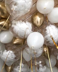 white and gold balloons are hanging from the ceiling in front of wooden planked walls