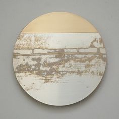 a white and gold plate on a gray wall with rusted paint in the middle