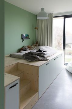 a bed sitting on top of a wooden platform next to a window in a bedroom