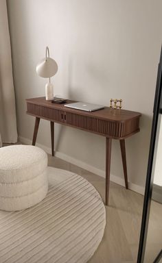 a table with a lamp on it next to a white round rug and a window