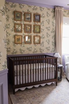 a baby's crib in the corner of a room with floral wallpaper