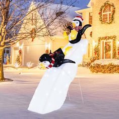 an inflatable snowman and penguin riding on top of a surfboard outside