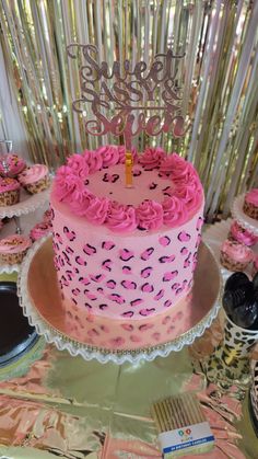 a birthday cake with pink frosting and sprinkles is on a table