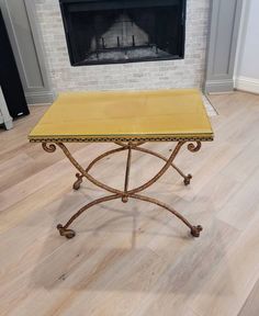 a yellow table sitting on top of a hard wood floor next to a fire place