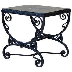 an iron table with a marble top and scrolled design on the bottom, against a white background