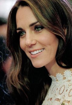 a close up of a person wearing a white dress and smiling at the camera with green eyes