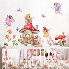 a baby crib with fairy wall decals and stuffed animals in the crib