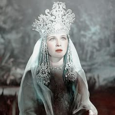 a woman wearing a tiara and veil in front of a painting with trees behind her