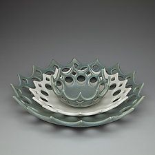 a white and green bowl with an intricate design on it's side, sitting on a gray surface