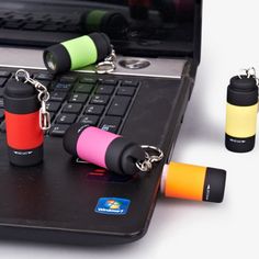 several lighters are sitting on top of a laptop keyboard and keychains attached to the keys