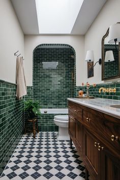 a bathroom with green tiles on the walls and floor, along with a black and white checkered tile floor