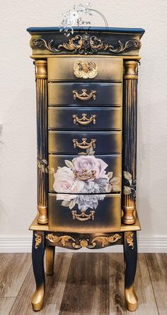 a gold and black dresser with flowers painted on it