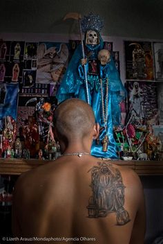 a man with tattoos on his back standing in front of a statue