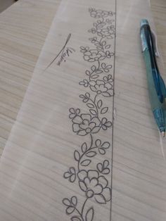 a pen is sitting on top of a piece of paper that has flowers drawn on it