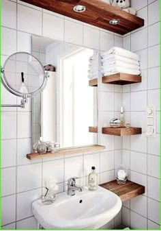 a bathroom with white tile and wooden shelves on the wall, along with a sink