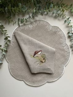 a white plate topped with a napkin next to some green leaves and plants on top of it