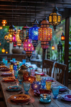 an outdoor dining table with many colorful lights hanging from it's ceiling and plates on the table