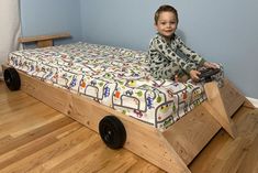 a young boy sitting on top of a bed with wheels attached to the mattress frame