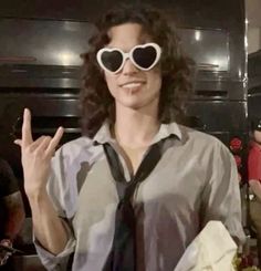 a woman wearing heart shaped sunglasses and a tie with her hand up in the air