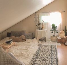 an attic bedroom with white walls and wooden flooring is furnished with various items on the bed