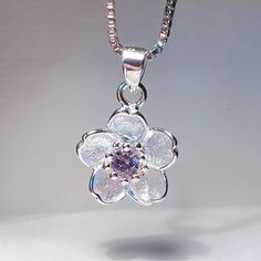 Gorgeous Sakura Flower Pendant. This Dainty, Elegant Pendant Features A Beautiful Silver Flower With A Simulated Purple Diamond Core. Pendant: 0.5” Necklace: 18" Silver Flower Necklace For Anniversary, Blossom Color Sterling Silver Flower Jewelry, Silver Delicate Flower Charm Necklace, Blossom Colored Flower-shaped Sterling Silver Jewelry, Delicate Silver Flower Charm Necklace, Silver Flower Charm Necklace For Her, Silver Flower Charm Necklace As Gift For Her, Dainty Silver Flower Charm Necklace, Elegant Sterling Silver Flower Necklace