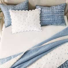 a bed with blue and white comforters and two pillows on top of the headboard