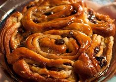 there are many cinnamon buns on the plate with chocolate sauce around them and drizzled with icing