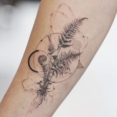 a tattoo on the arm of a person with a fern and moon in it's center