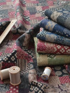 several different types of quilts and thread on a tablecloth with some sewing needles