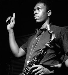 a black and white photo of a man holding a saxophone in his right hand while standing next to another man