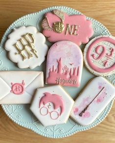 some cookies are on a plate with pink and white icing in the shape of letters