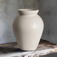 a white vase sitting on top of a wooden table