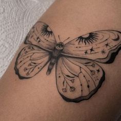 a black and white tattoo of a butterfly on the back of a woman's thigh