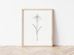 a drawing of a flower in a wooden frame on the floor next to a wall