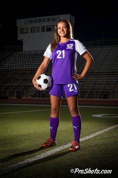 a female soccer player is posing for a photo on the field with her soccer ball