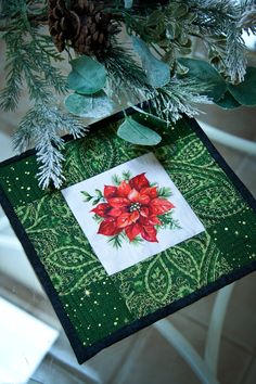 a christmas ornament hanging from a tree with pine cones and greenery on it