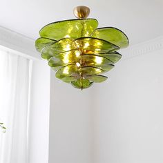 a green chandelier hanging from the ceiling in a room with white walls and windows