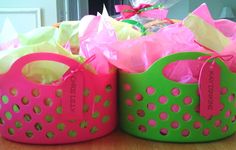 two green and pink baskets sitting on top of a wooden table