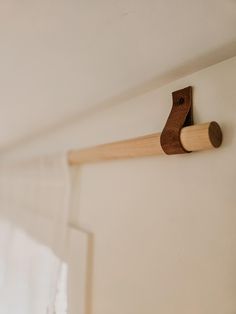 a close up of a wooden object on a wall near a curtain rod and window