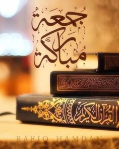 three books with arabic writing on them are sitting on a wooden table in front of a blurry background