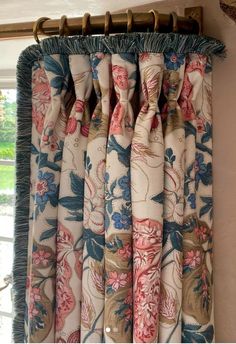 the curtains are hanging on the window sill in front of an open window with blue and pink flowers